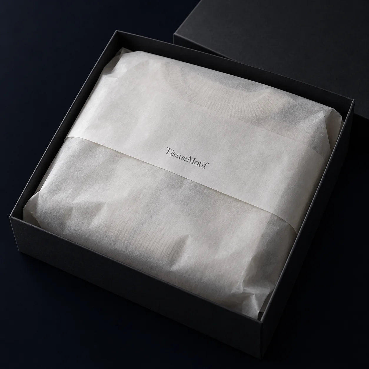 A single understated wordmark centered on the tissue fold of a wrapped gift box