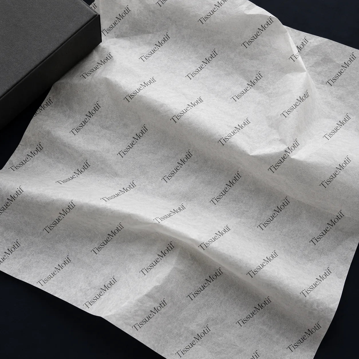 Small charcoal TissueMotif wordmarks repeated diagonally across a natural white tissue sheet