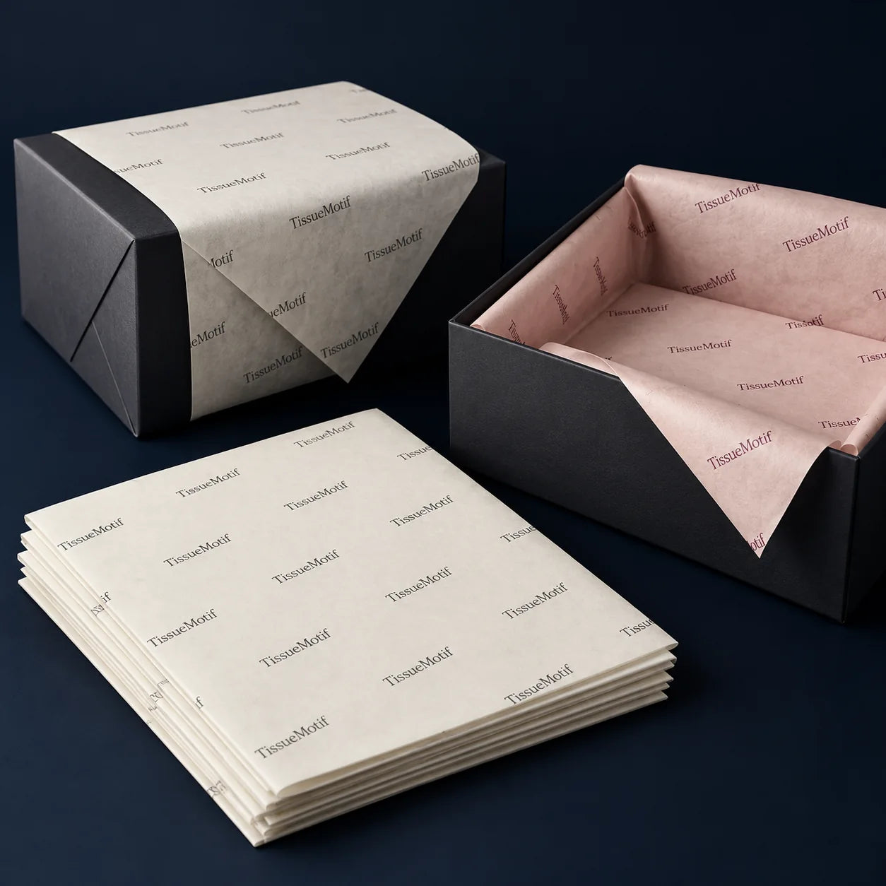 A stack of printed tissue beside wrapped boxes and a blush tissue-lined gift box